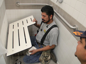 Worker Lupe Garcia finishes assembling a chair in one of the showers at the Fitness Center. Photo by Monica Lamadrid