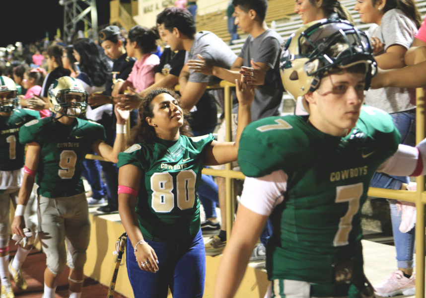 Trinity Chavez and her teamates high five students lined up along the rails of the stands at Harlendale Memorial Stadium. She is the only female on the school’s football team.