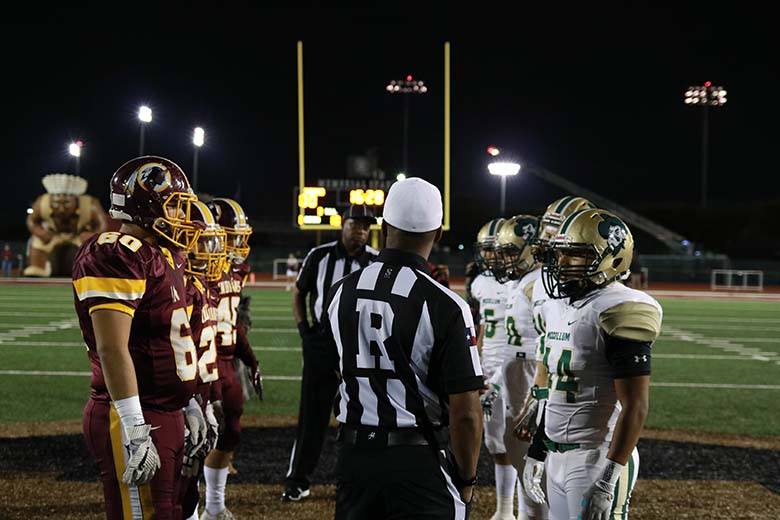 Captains from Harlandale and McCollum meet at midfield ahead of the 54th Frontier Bowl. The two teams share the stadium; this year, the Indians sat on the home side of the stadium. Photo by Jose Arredondo.